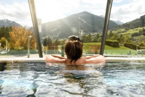 Frau entspannt in der Alpentherme Gastein mit Blick auf die Berge – Wellnessurlaub mit Hund in Österreich